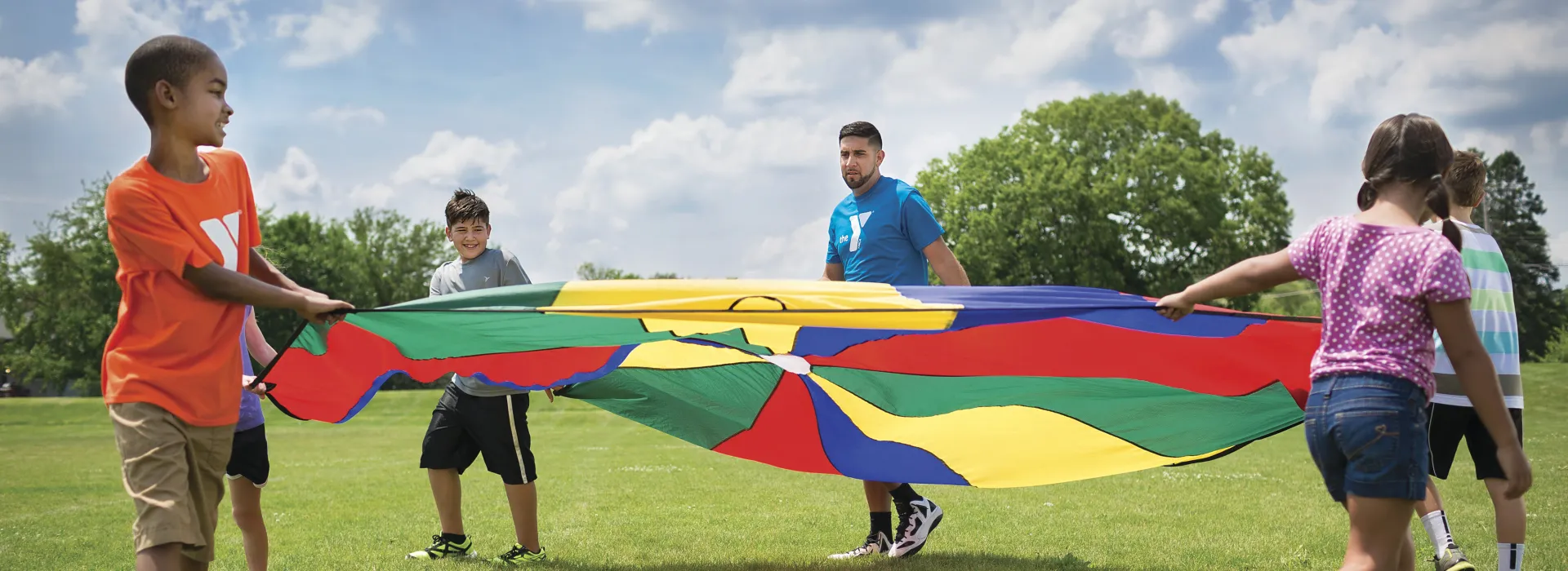 students playing outdoors with a parachute